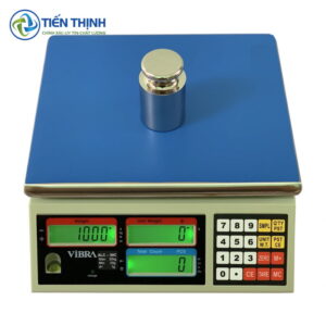 Cân điện tử hiện đại với màn hình hiển thị số và vật chuẩn.