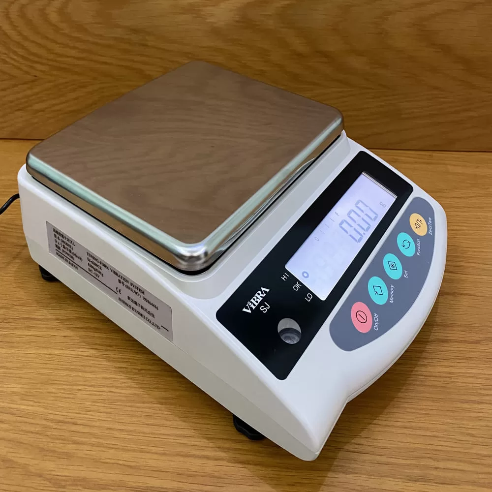 Cân điện tử kỹ thuật số màu trắng với mặt bàn vuông bằng thép không gỉ.