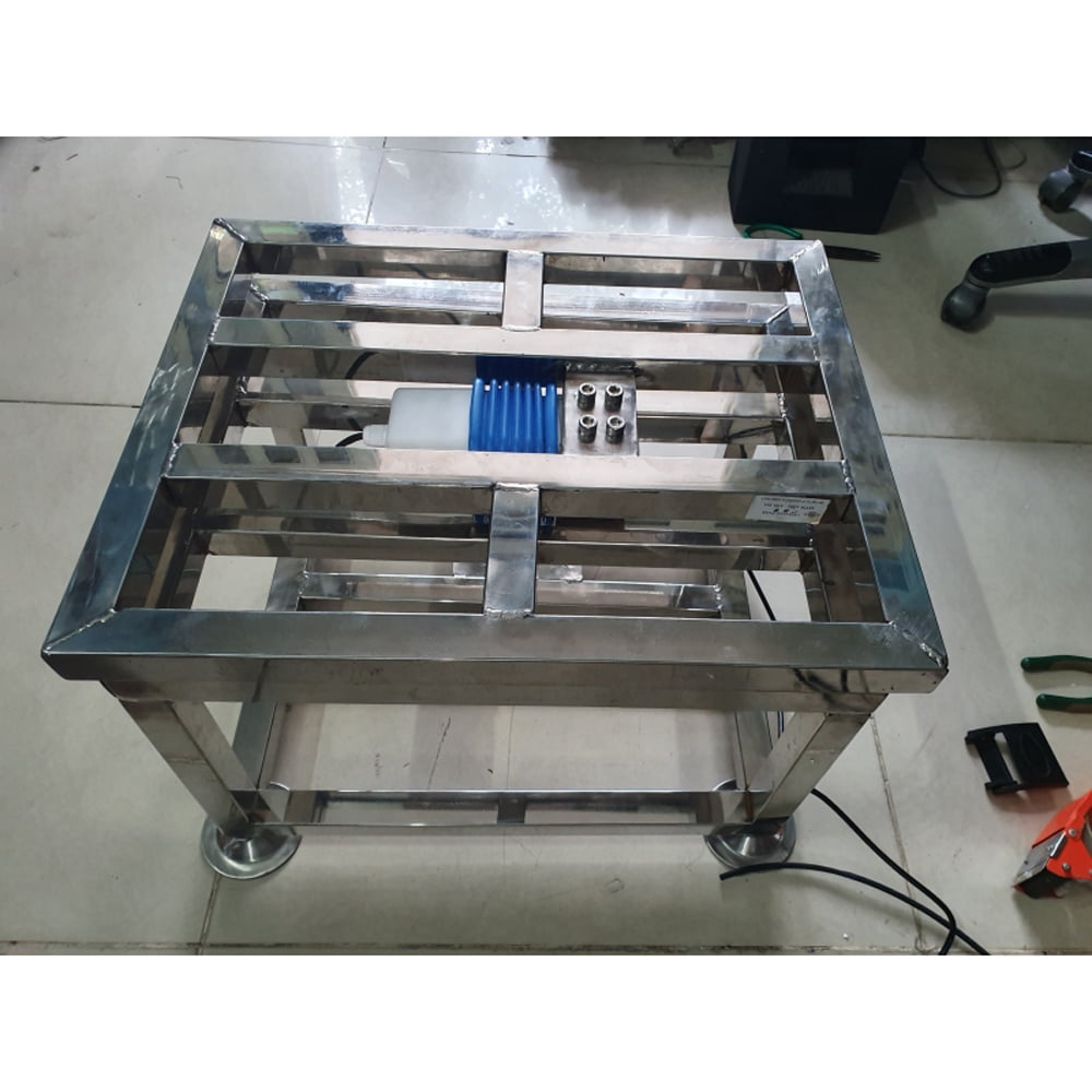 Khung kim loại vuông vức, gắn thiết bị màu xanh, có bánh xe.