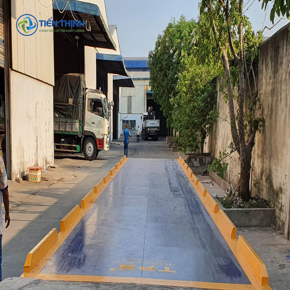 Cân xe tải lớn đặt ngoài trời, có người và xe đang chờ.