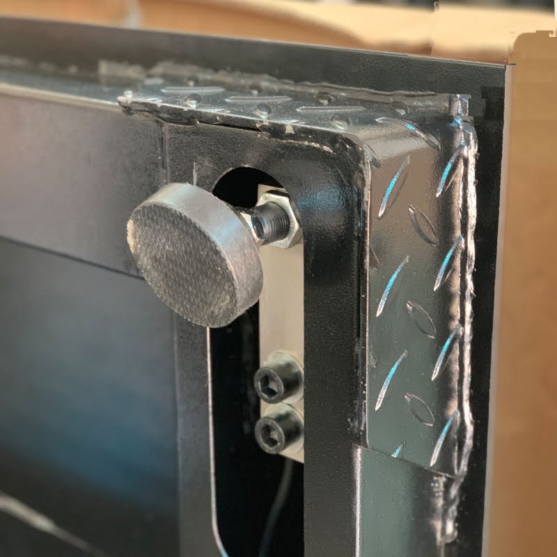 Chi tiết bản lề kim loại đen với núm vặn tròn.