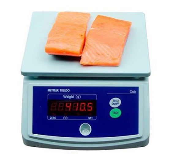 Cân điện tử đang cân hai miếng cá hồi tươi màu cam hồng.