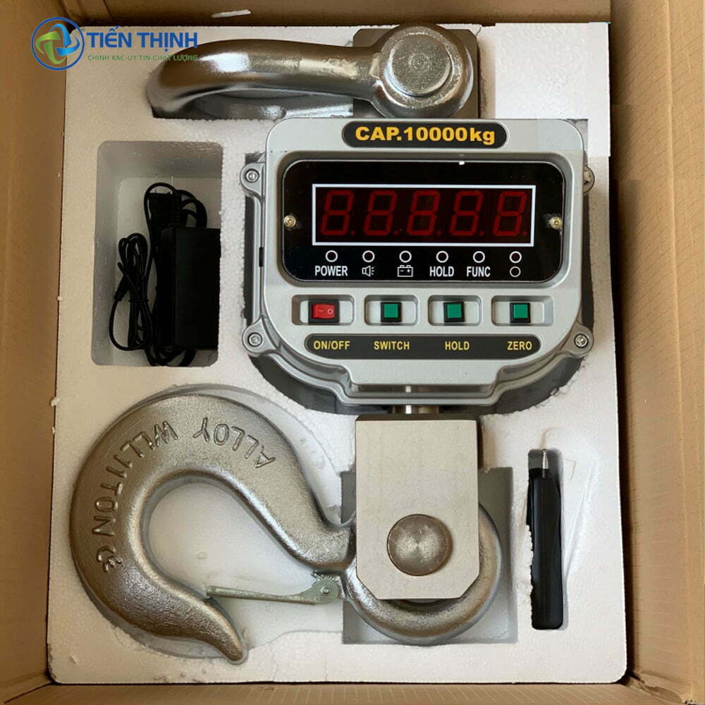 Cân treo điện tử hiển thị số, kèm móc treo và phụ kiện trong hộp.