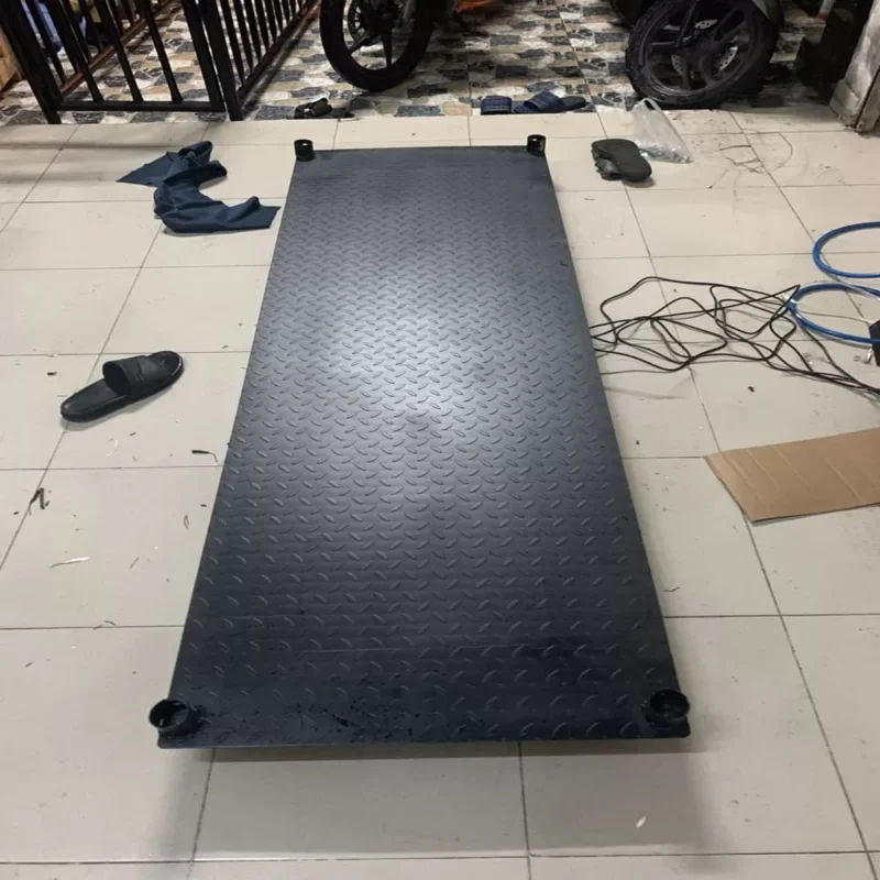 Sàn nâng nền đen hình chữ nhật, có các chân trụ nhỏ, đặt trong nhà.