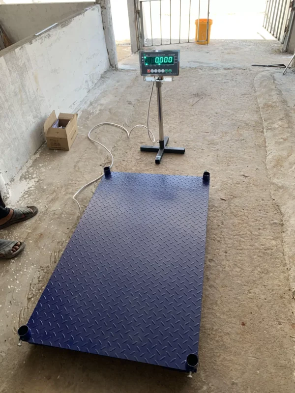 Cân điện tử sàn màu xanh đen trong một không gian xây dựng.