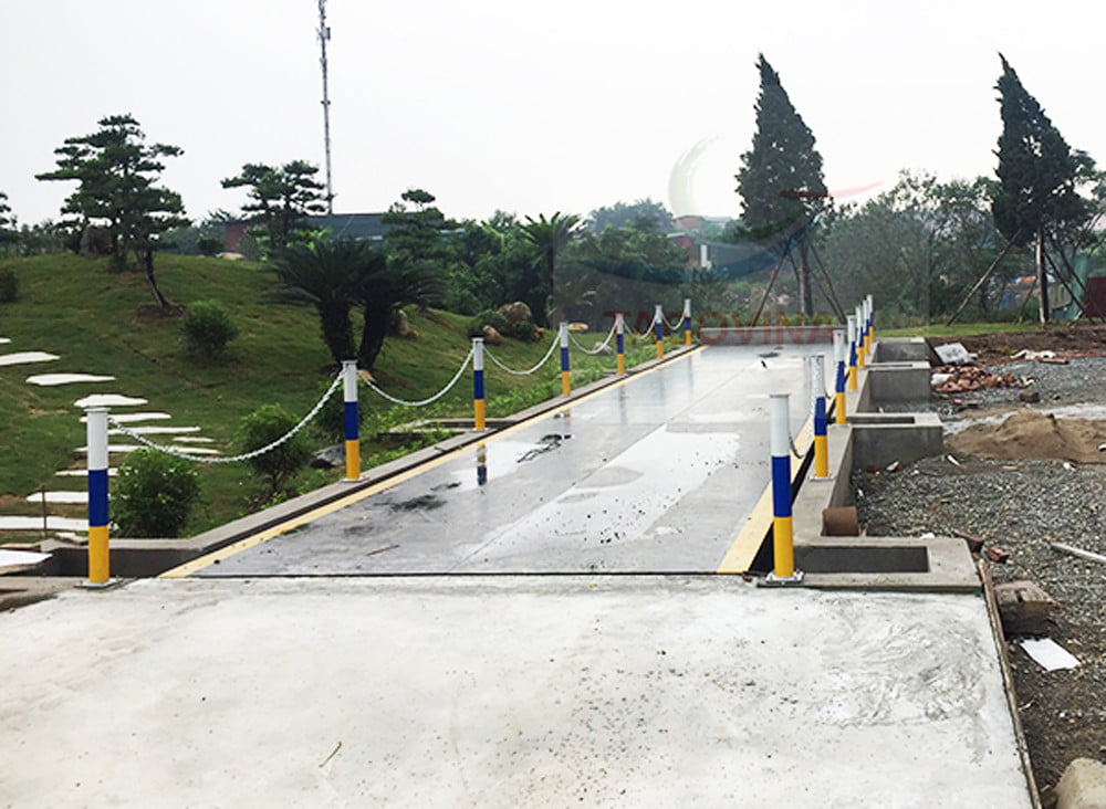 Cầu bê tông mới xây, lan can xích vàng trắng, quang cảnh xanh mát.