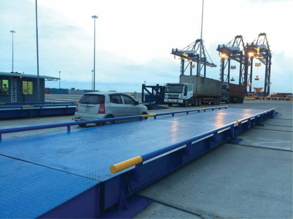 Cảng biển nhộn nhịp với xe cộ và các thiết bị xếp dỡ hàng hóa.