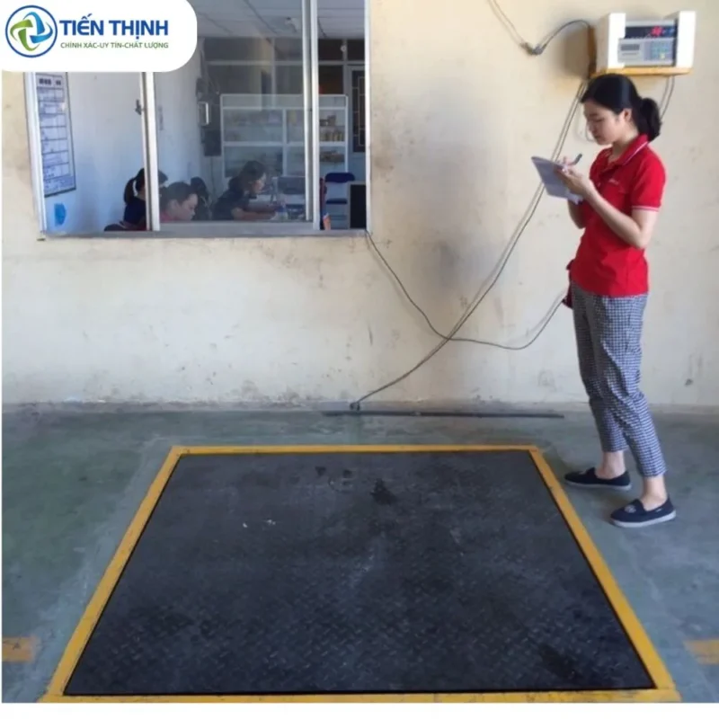 Một nhân viên đang ghi chép dữ liệu bên cạnh cân ô tô công nghiệp.