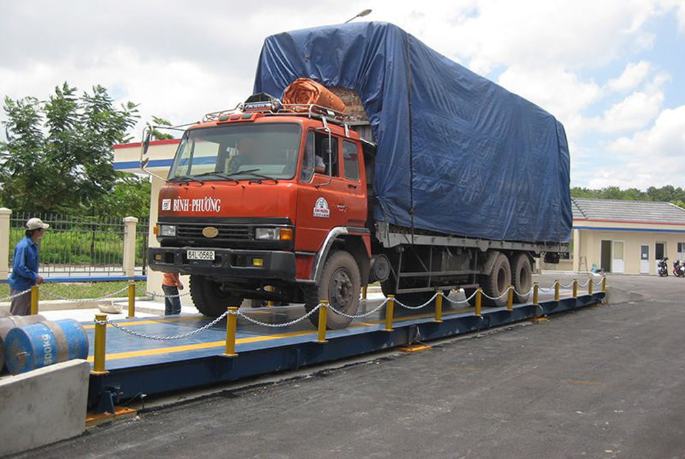 Xe tải lớn màu cam đang cân hàng tại trạm cân tải trọng.