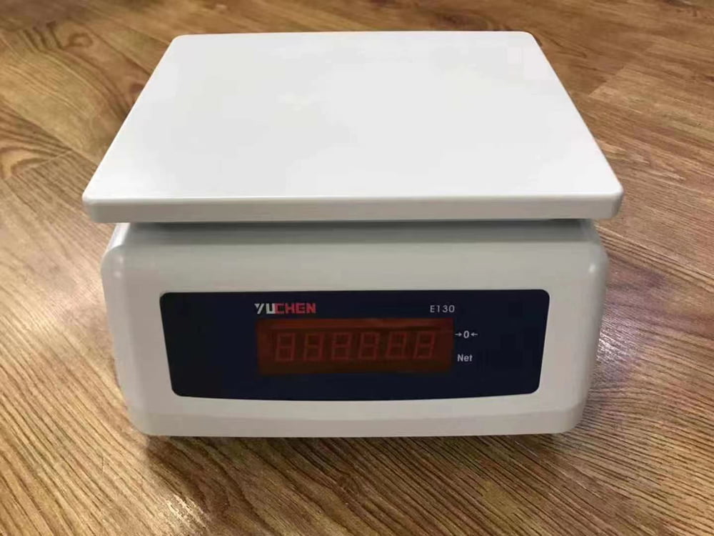 Cân điện tử màu trắng với màn hình hiển thị số màu đỏ.